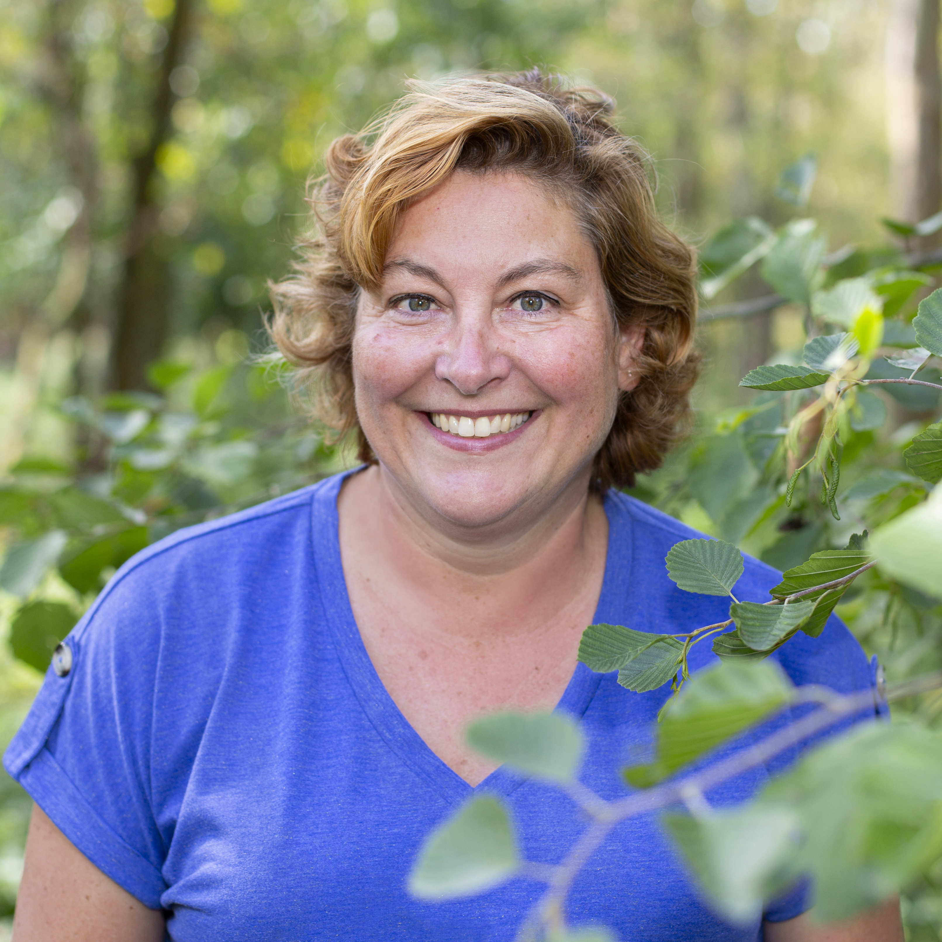 Bianca standing next to a tree in the forest.
