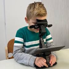 Jongen kijkt door een biopter tijdens een visuele screening.